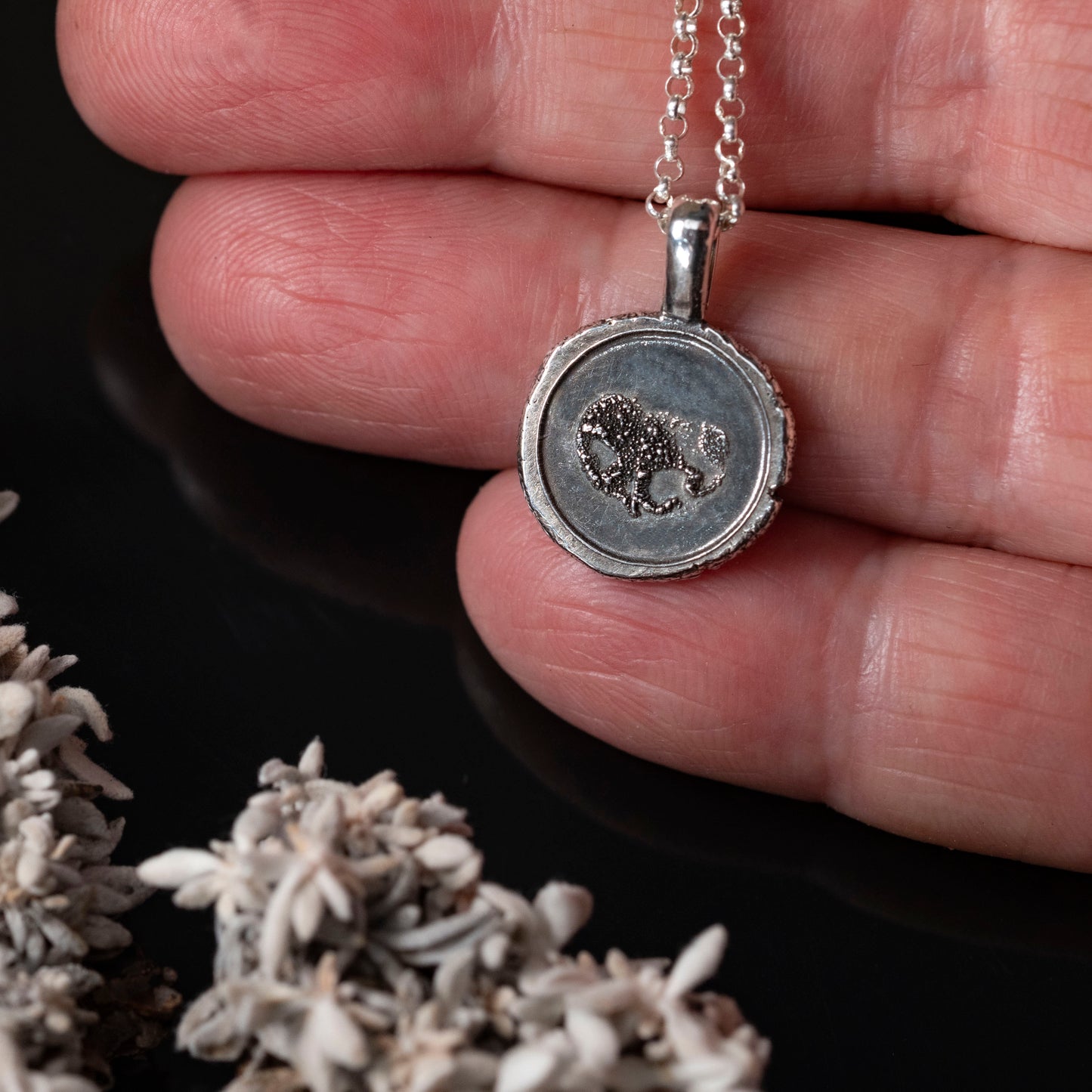 details of silver pendant with dog nose imprint