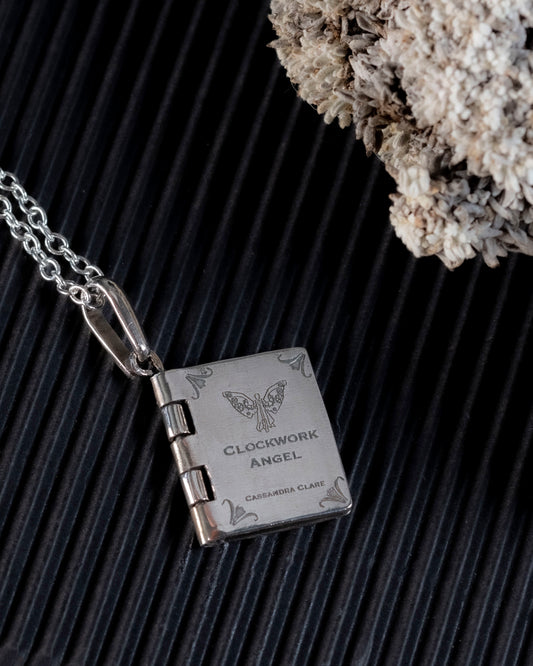 Close-up of the laser-engraved clockwork angel on the book pendant cover
