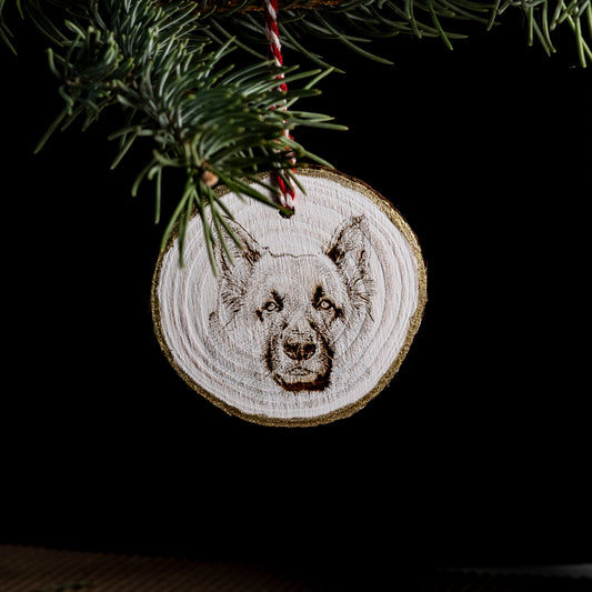 Wooden ornament with a dog's face design hanging on a Christmas tree.