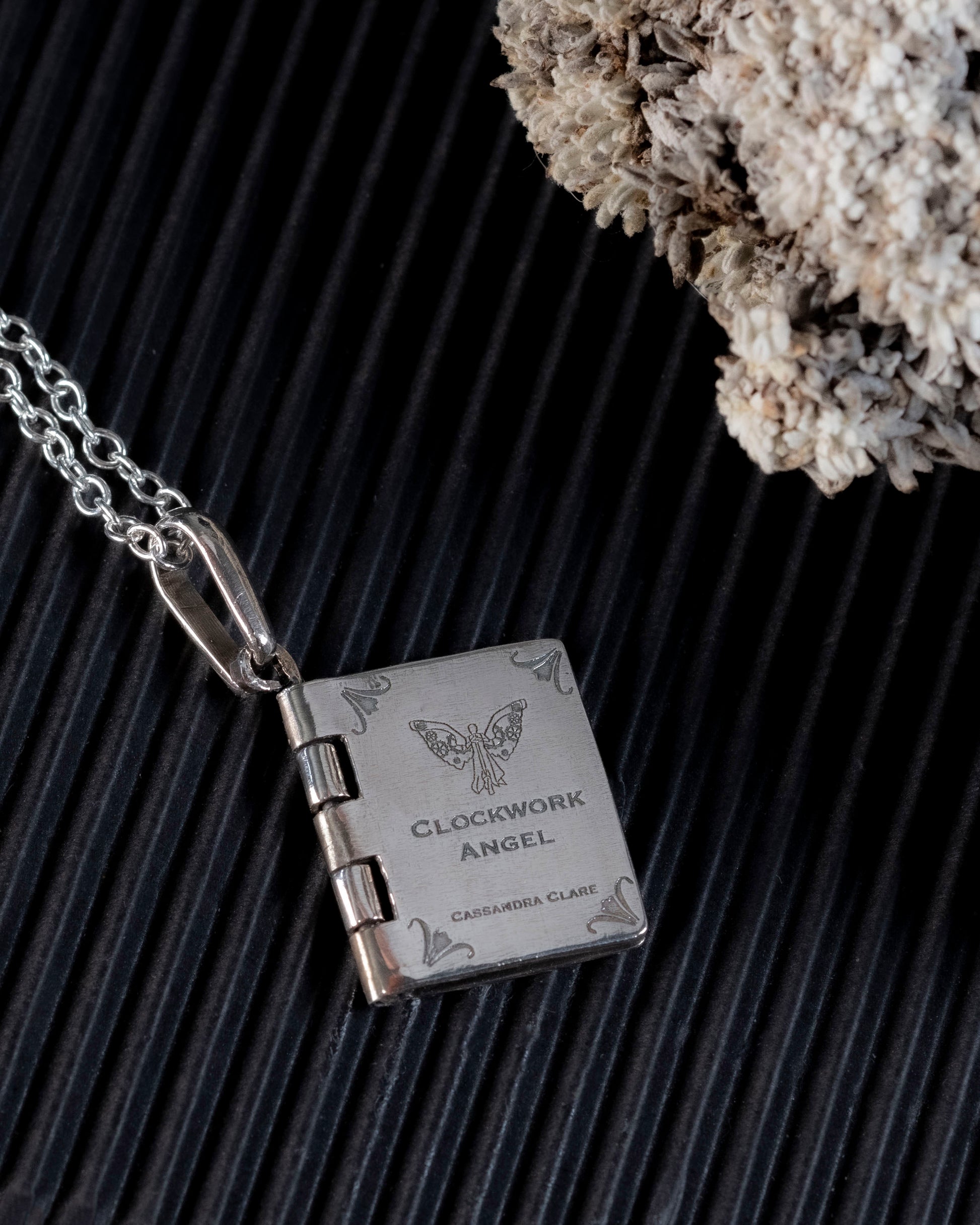 Close-up of the laser-engraved clockwork angel on the book pendant cover