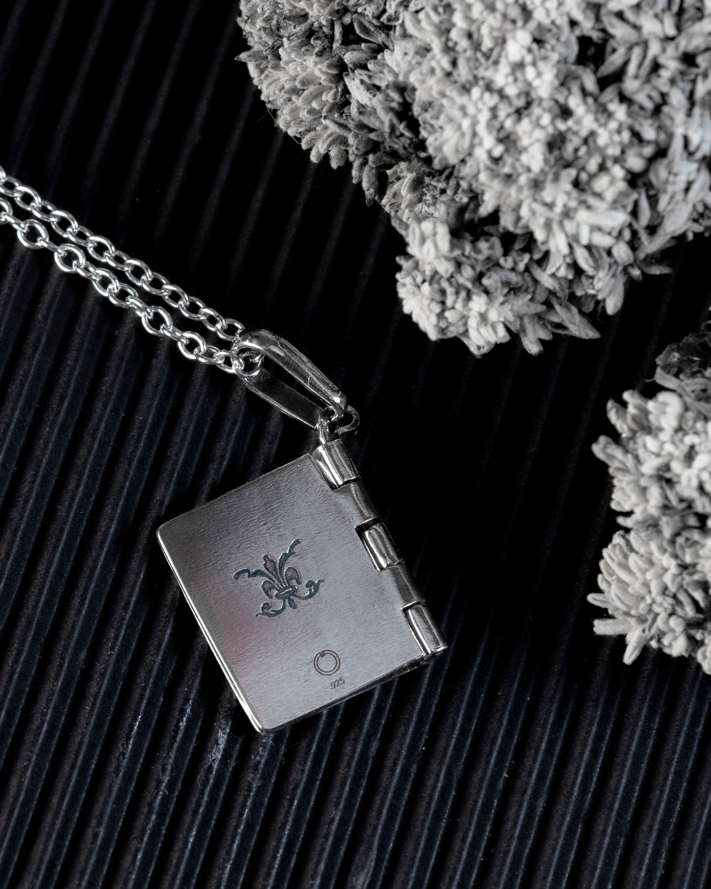 The back of the silver book pendant with a flourish engraving.