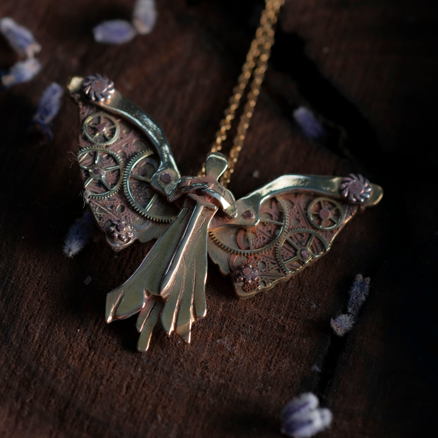 A close-up of a brass clockwork angel necklace with intricate gear details