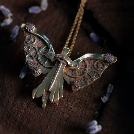 A close-up of a brass clockwork angel necklace with intricate gear details